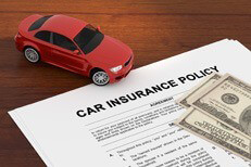 Car insurance policy on desk with small toy car and one hundred dollar bills