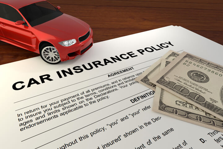 Car insurance policy on desk with red car and one hundred dollar bills