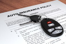 Auto insurance policy and car keys on wood table
