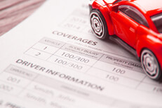 Auto insurance policy showing coverages and driver information with red toy car