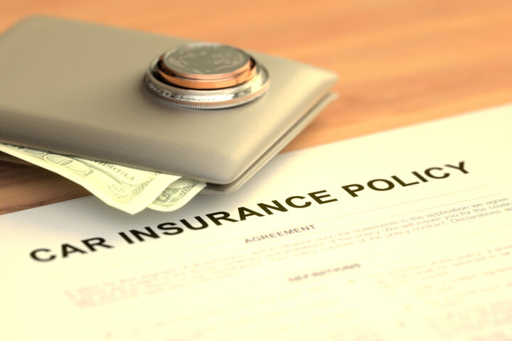 Wallet with cash and stack of coins on table with car insurance policy