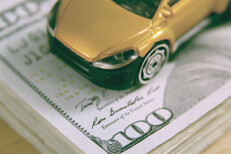 Toy car on stack of one hundred dollar bills