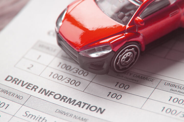Toy car on top of auto insurance policy showing driver information