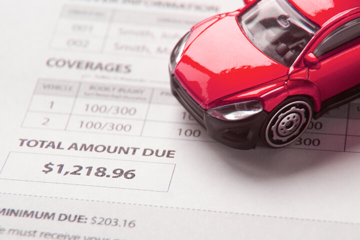 Auto insurance bill showing total amount due with small red toy car