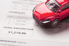 Auto insurance bill showing total amount due with small red toy car
