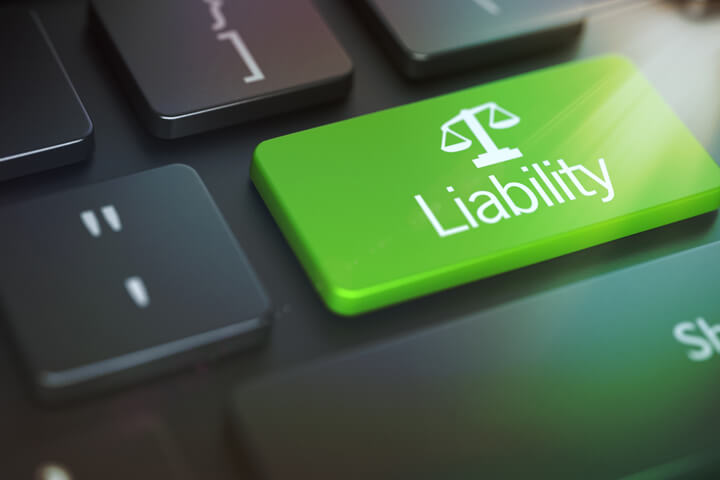 Dark laptop keyboard with green Liability key and corner lens flare