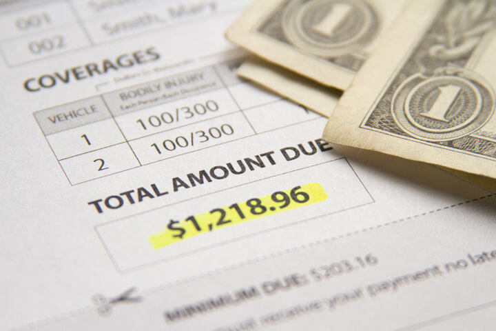 Car insurance policy showing total amount due with dollar bills
