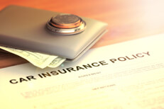 Wallet with coins and cash on car insurance policy with light flare and overlay effect