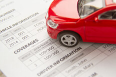 Red toy car on a car insurance policy showing vehicle and driver information and coverages