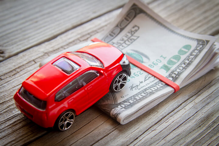 Red SUV climbing folded 100 dollar bills car insurance or automotive cost concept photo