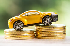 Yellow toy car climbing two stacks of gold coins