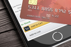Credit card lying on top of iPhone with Amazon app visible on screen with focus on Add to Cart button