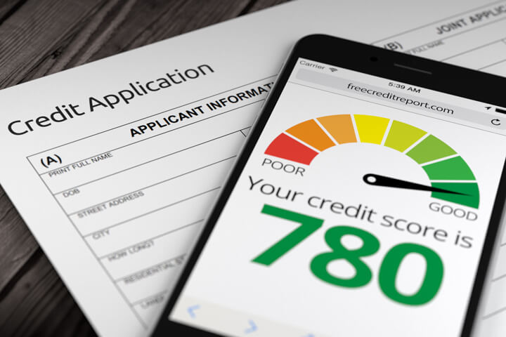 Paper credit application on desk with mobile phone showing good credit score of 780