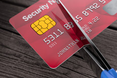 Top view of scissors cutting through red credit card