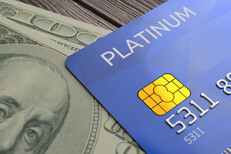 Credit card on currency Blue platinum credit card lying on top of one hundred dollar bill