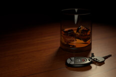 Drunk driving concept showing alcoholic drink on bar with car keys in foreground