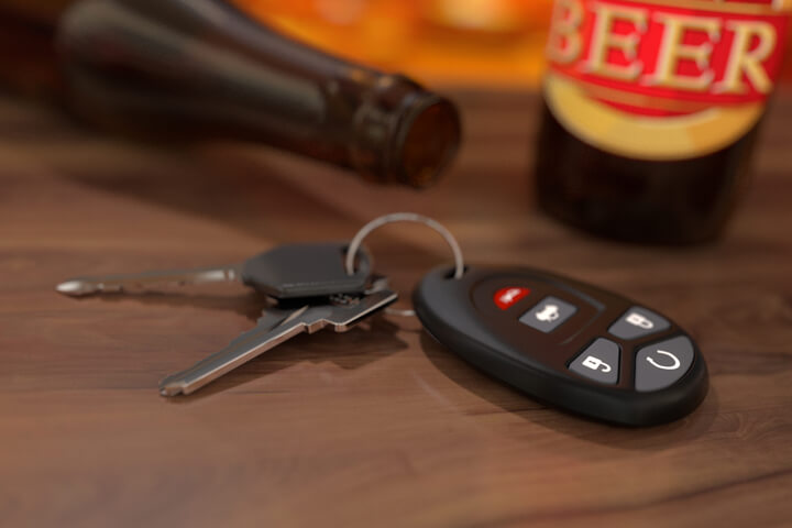 Car keys on wood bar with beer bottles in background