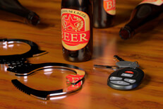 Shiny handcuffs with car keys and beer bottles on bar DUI concept image
