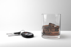 Drunk driving concept of glass of bourbon whiskey and car keys on a white studio background