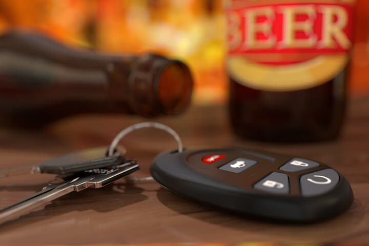 Car keys and clicker with beer bottles on bar at happy hour DUI concept image