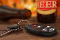 Car keys and clicker with beer bottles on bar at happy hour DUI concept image