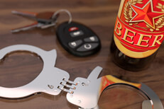 Car keys with hand cuffs and a beer bottle sitting on bar free DUI image
