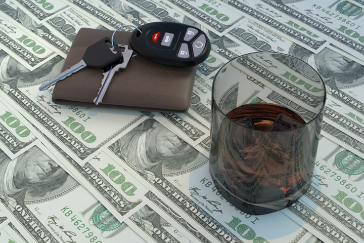 Glass of whiskey, wallet, and car keys on top of money concept for the cost of driving under the influence