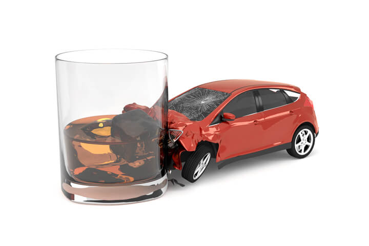 Drunk driving concept showing small red car crashed into side of whiskey glass isolated on white