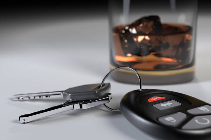 DUI concept showing whiskey glass and car keys on white studio backdrop