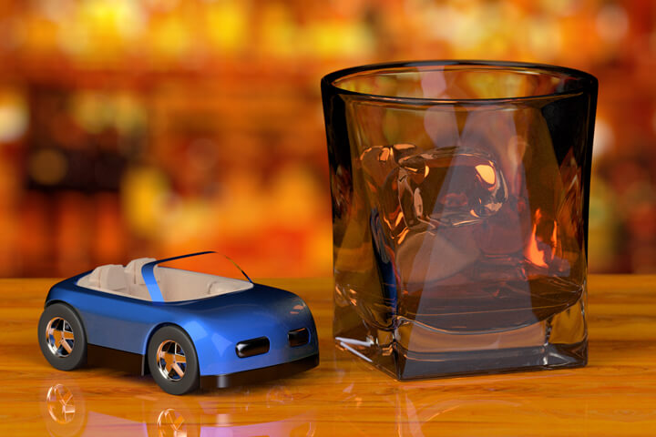 Glass of whiskey and toy car on bar with liquor bottles in background free DUI image
