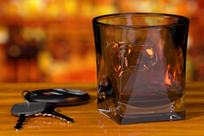 Whiskey glass and car keys on bar with liquor bottle background DUI concept
