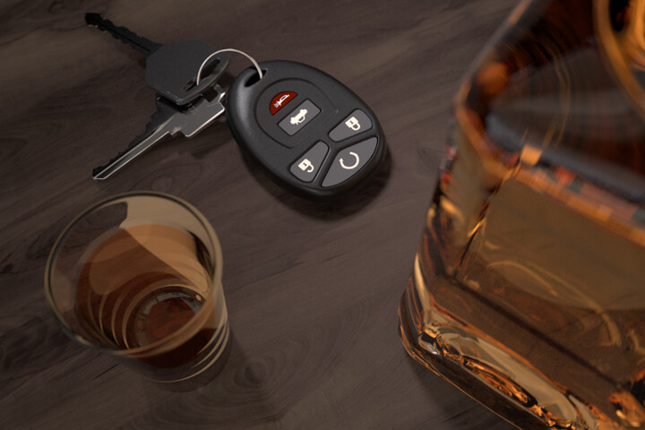Whiskey bottle and shot glasses on wood bar with car keys DUI concept image
