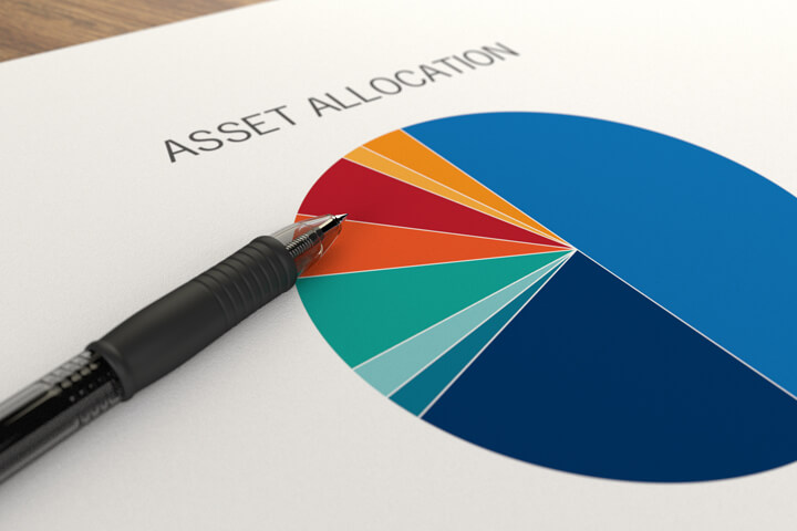 Paper with asset allocation pie chart overlaid with ballpoint pen on table