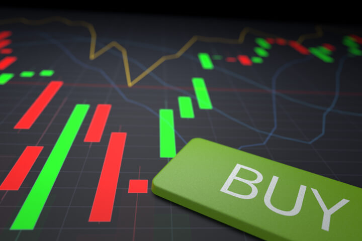Buy key from laptop on top of stock candlestick chart showing stock price ranges by day
