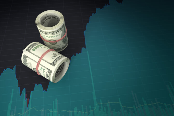 Rolls of U.S. currency on computer screen with stock price area chart