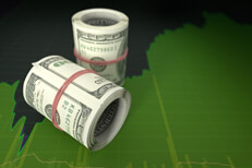 Two rolls of U.S. bills laying on top of bright green stock price area chart