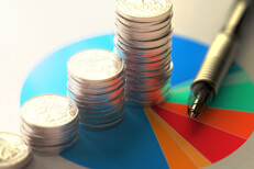 Paper with asset allocation pie chart, stacks of coins, and ballpoint pen