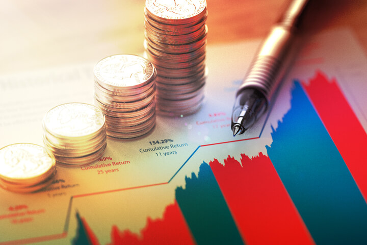 Paper with historical stock market returns chart and stacks of coins representing investment growth over time