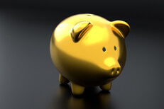 Shiny gold metallic piggy bank on dark studio background and soft lighting