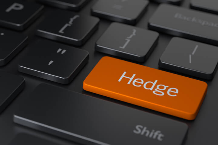 Dark computer keyboard with large orange Hedge key representing hedging investments online