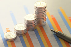 Column chart showing investment returns with increasing stacks of coins and ballpoint pen