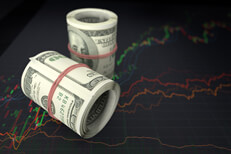 Money rolls sitting on stock price line charts