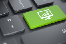 Dark computer keyboard with bright green key showing a monitor with increasing column chart
