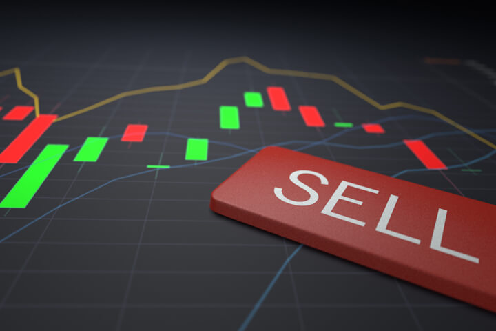 Sell keyboard key on stock price candlestick chart representing stock sale