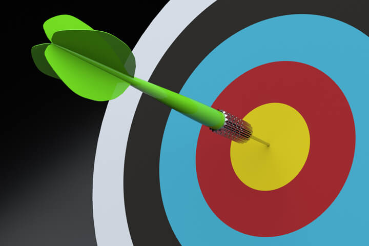 Green dart in center of colorful target on dark background