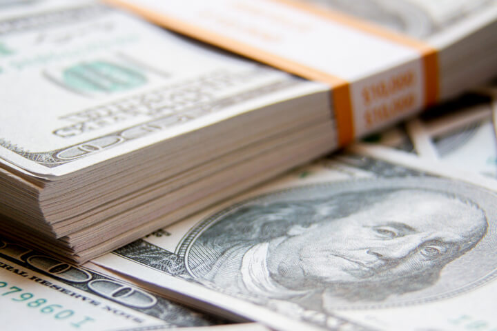 Stack of $10,000 banded bills with scattered 100 dollar bills