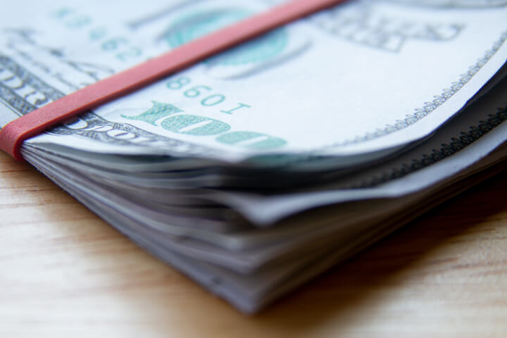 Corner view of folded $100 bills with rubber band