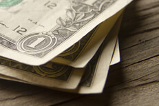 Random stack of dollar bills on wood background