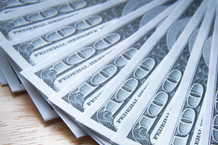 $100 bills evenly fanned out on wood table close up photo