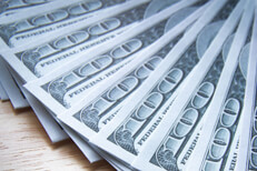 $100 bills evenly fanned out on wood table close up photo